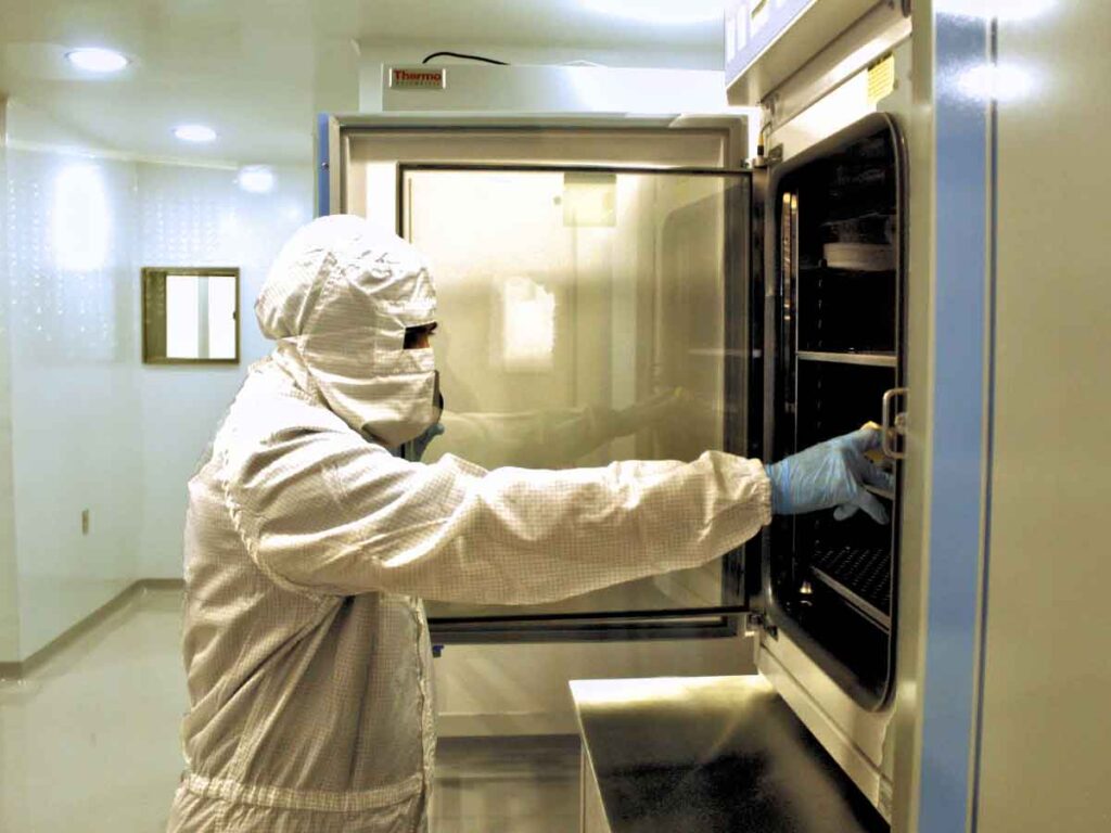 A lab technician in full safety gear carefully places stem cells into a deep freezer at the new Verita Neuro Mexico stem cell lab, highlighting the meticulous handling and storage processes in the facility.