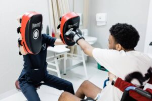 Patient practicing boxing exercises during neurorehabilitation, illustrating neuroplasticity exercises for spinal cord injury recovery and improved motor control.