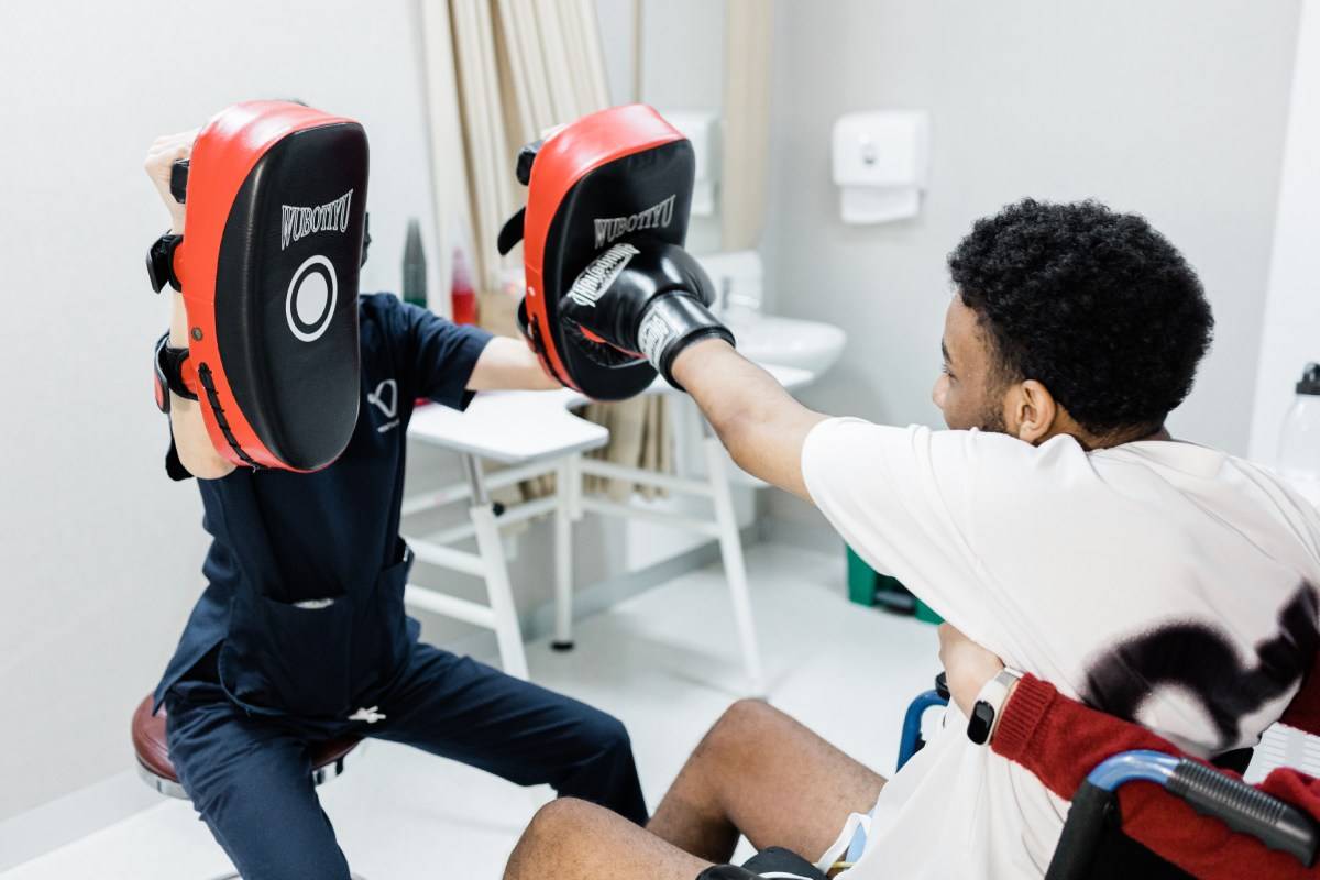 Patient practicing boxing exercises during neurorehabilitation, illustrating neuroplasticity exercises for spinal cord injury recovery and improved motor control.