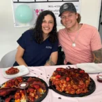 Brock, a T6 Complete Spinal Cord Injury patient, is pictured alongside Attending Physician Dr. Paulina Marin at Verita Neuro in Mexico. They are both smiling in front of a table laid with food.