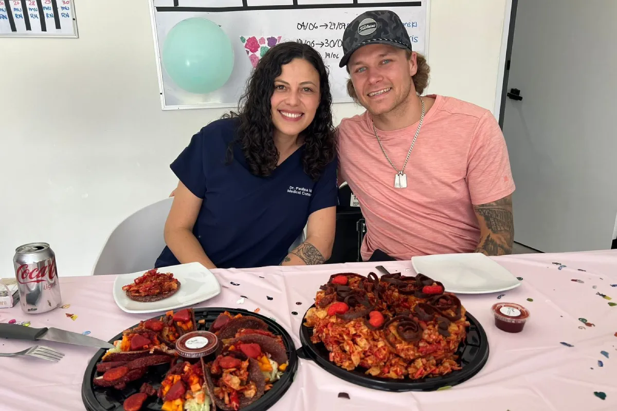 Brock, a T6 Complete Spinal Cord Injury patient, is pictured alongside Attending Physician Dr. Paulina Marin at Verita Neuro in Mexico. They are both smiling in front of a table laid with food.