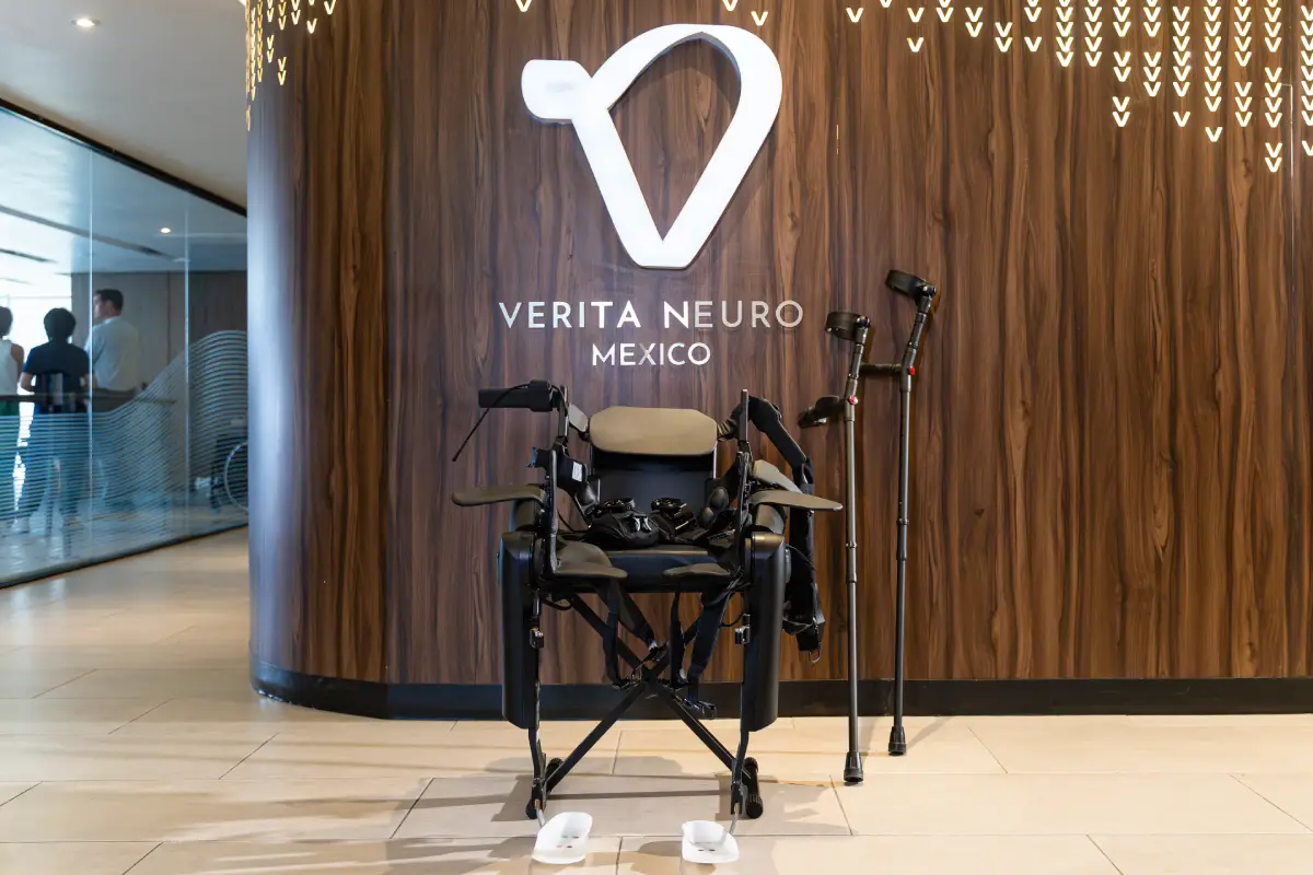 ReWalk Personal Robotic Exoskeleton with crutches displayed on a chair in Verita Neuro facilities against a wall with Verita Neuro logo